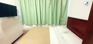 a small room with a bed with a green curtain at Bayu Inn in Kota Kinabalu