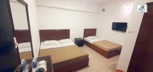 a small bedroom with two beds and a mirror at Bayu Inn in Kota Kinabalu