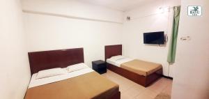 a small room with two beds and a tv at Bayu Inn in Kota Kinabalu