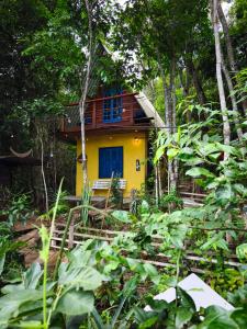 a yellow house with a blue door in the forest at Chalé no Plantar em Casa in São Roque