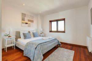 a white bedroom with a bed and a window at Beach Villa with Jacuzzi & Garage by HostWise in Vila Chã