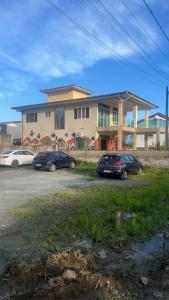 two cars parked in front of a large house at Hostel Ôxe in Paraty