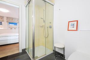 a glass shower in a bathroom with a stool at Ferienhaus Cäcilienhof West in Kampen +54 photos