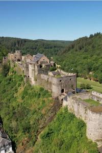 an old castle on a hill with houses at Label Semois-L'Orée des sens-Bain nordique privé in Bouillon