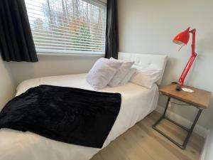 a bedroom with a bed with a red lamp and a window at The Hideaway on Tacketts - Shipping Container in Hurricane