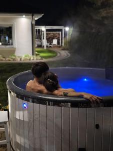 a man and woman in a hot tub at night at Sosenkowe Apartamenty Balia & Jacuzzi in Kuźnica Głogowska +36 photos