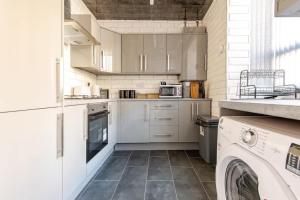 a kitchen with white cabinets and a washer and dryer at Cosy Brierfield house with fireplace and parking in Brierfield