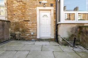 a white door on the side of a brick building at Cosy Brierfield house with fireplace and parking in Brierfield +15 photos