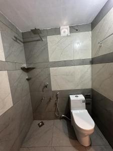 a bathroom with a toilet and a tiled wall at Azriel marari in Mararikulam
