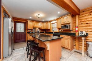 a kitchen with wooden cabinets and a large island with stools at Viva By The Stream by Railey Vacations in McHenry