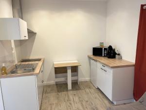 a small kitchen with white cabinets and a sink at Agreable studio proche du circuit du Mans in Arnage