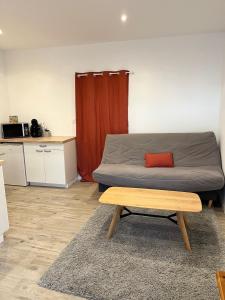 a bedroom with a bed with a red curtain and a table at Agreable studio proche du circuit du Mans in Arnage