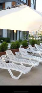 a group of white lounge chairs sitting under an umbrella at Belek Room Voyage in Belek