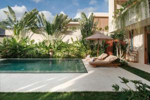 a backyard with a swimming pool and an umbrella at Manu Villas in Sanur