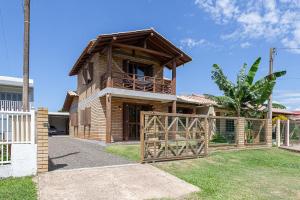 a wooden house with a gate and a fence at Casa de veraneio na Itapeva in Torres
