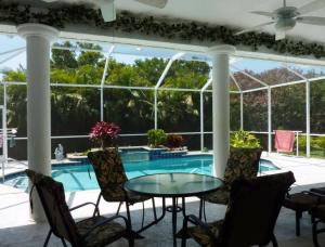 a patio with a table and chairs and a swimming pool at Villa Paloma in Cape Coral