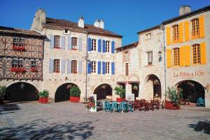 an old building with tables and chairs in a courtyard at La Lumière Dorée in Lauzerte