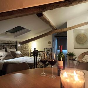 a table with two glasses of wine and a bed at La Lumière Dorée in Lauzerte