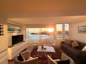 a living room with a couch and a table and a tv at Le Baloo vue sur mer in Ploemeur