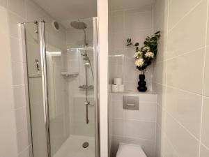 a bathroom with a shower and a toilet with a vase of flowers at Le Baloo vue sur mer in Ploemeur +24 photos