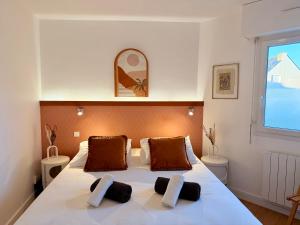 a bedroom with a large white bed with two pillows at Le Baloo vue sur mer in Ploemeur