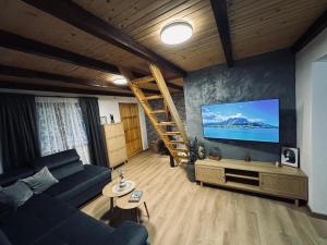 a living room with a couch and a large screen tv at Planinski šapat in Blidinje