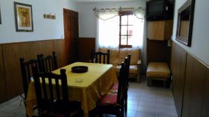 a dining room with a table and chairs and a kitchen at Los Cuatro Corazones in Villa Gesell