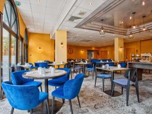 a dining room with tables and blue chairs at Mercure Trouville Sur Mer in Trouville-sur-Mer
