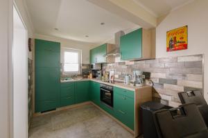 a kitchen with green cabinets and a brick wall at Premium-Plus-Ferienhaus Havanna Select in Hasselfelde