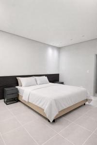 a white bedroom with a large bed with white walls at Luxuoso Apartamento 2 quartos no Centro in Imperatriz