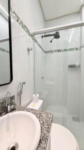 a white bathroom with a sink and a shower at Luxuoso Apartamento 2 quartos no Centro in Imperatriz