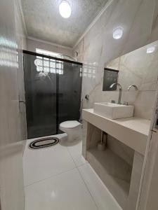 a bathroom with a shower and a toilet and a sink at Casa praia e piscina in Bertioga +5 photos