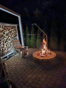 a fire pit with a bench and a chair next to it at Sosenkowe Apartamenty Balia & Jacuzzi in Kuźnica Głogowska