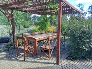 a wooden table and bench under a wooden pergola at Domo familiar campestre in La Montaña