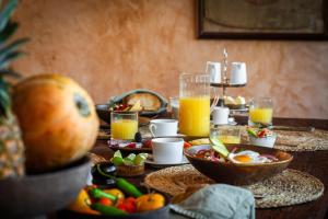 a table with breakfast foods and orange juice at Coco Lou - Private Villa with Rooftop Pool in Holbox Island
