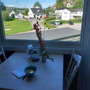 a table with a vase of flowers on it next to a window at Central functional apartment with short distance to everything in Sandefjord