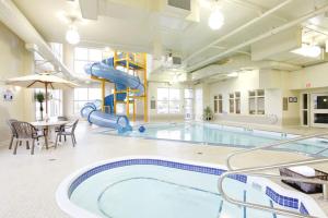 a large swimming pool with a slide in a building at Vegreville Suites in Vegreville