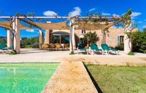 a pergola with chairs and a pool in front of a house at Can Carrio in Son Servera
