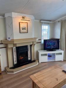 a living room with a fireplace and a tv at West Cumbria static caravan in Workington