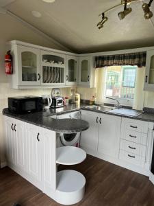a kitchen with white cabinets and a black counter top at West Cumbria static caravan in Workington