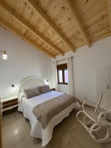 a white bedroom with a large bed and chairs at La Ermita Casa Rural in Benablón +26 photos