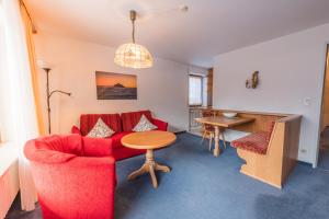 a living room with a red couch and a table at T13 Ferienwohnungen Schenk in Oberstdorf