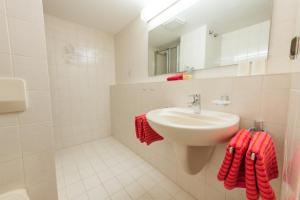a bathroom with a sink and a mirror and red towels at T13 Ferienwohnungen Schenk in Oberstdorf +22 photos
