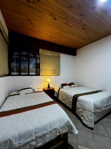 a bedroom with two beds and a wooden ceiling at Rajutuna Inn in Huaraz