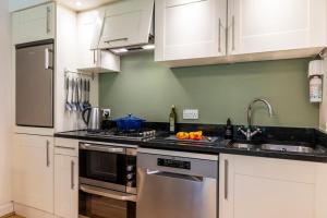 a kitchen with white cabinets and a stove top oven at Calder apartment Raven Wing in Fort Augustus +2 photos