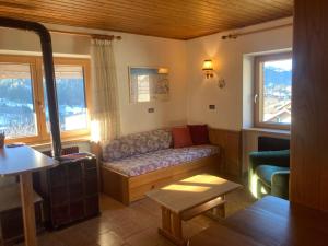 a living room with a couch and two windows at Casa Defrancesco in Panchià