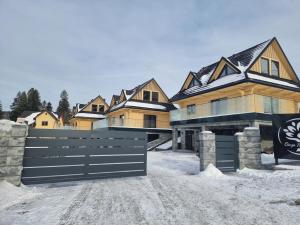 a house with a gate in the snow at Oaza Szczęścia in Koniaków