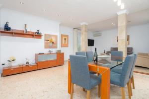 a living room with a glass table and blue chairs at Villa Sunset - San Antonio Bay in Cala de Bou