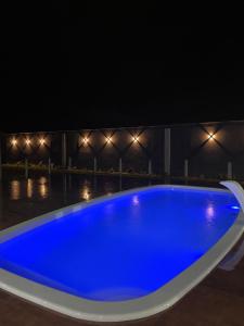 a blue swimming pool at night with lights at Mansão Xodó in Marataizes