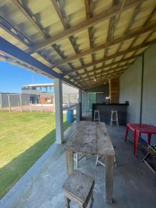 a picnic table and two stools under a pavilion at Mansão Xodó in Marataizes